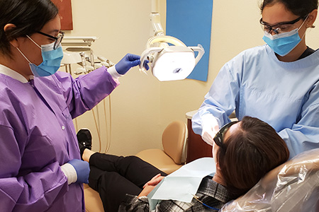 Dental patient in examination chair with two dental professionals