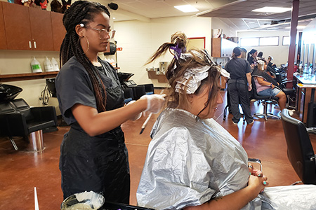 Hair student providing hair color services to a member of the community