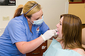 Female dental clinic student looking into female patient's mouth